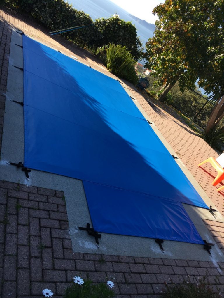 Cobertor de piscina confeccionado en tejido microperforado con anclajes mediante tornillería en inox. escamoteable y sistema de cincha.